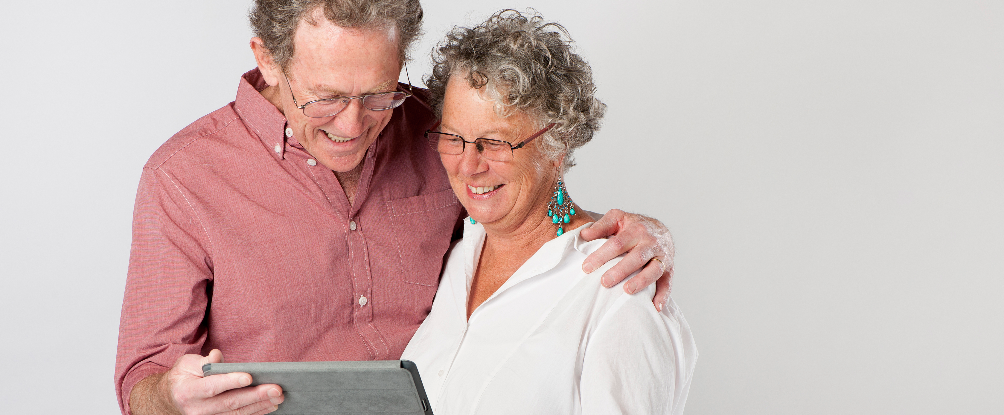 Man and woman smiling, holding iPad
