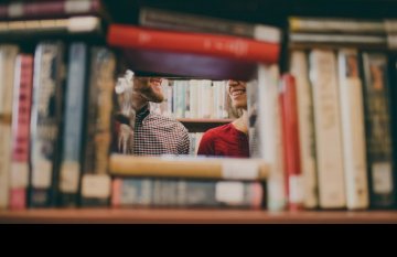 View of couple through a book shelf