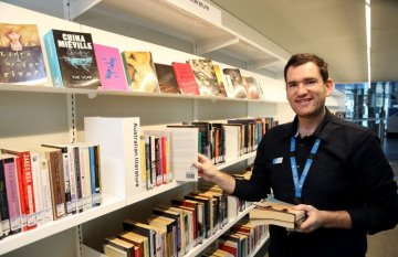 Male librarian returning books to shelf