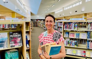 Interior of Colac Library showing Mayor Cr Kate Hanson holding some books and smiling