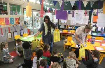 school children sitting on floor receiving bags from librarian