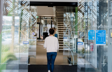 Woman walking through glass doors into Waurn Ponds Library