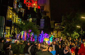 Geelong Library and Heritage Centre colourfully lit at night with a crowd of people during the 2019 Geelong After Dark festival.
