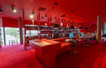 Interior of red room - floors and wall and shelving same colour. Table in centre of image.