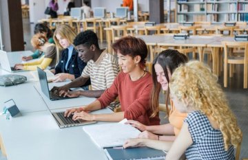 A group of diverse young adults, working together on their laptops